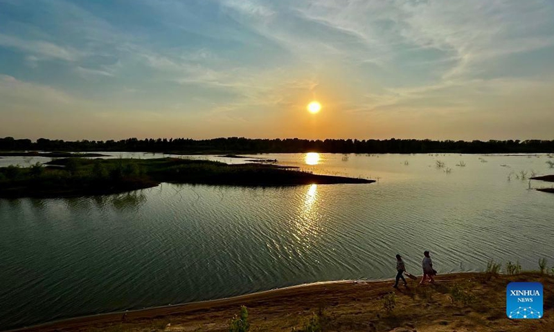 Photo taken with a mobile phone shows people walking along the Yongding River at sunset in Daxing District of Beijing, capital of China, May 30, 2021.Photo:Xinhua