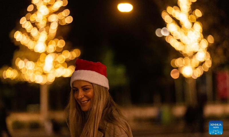 A woman is seen in front of festive lights in Athens, Greece, on Dec. 5, 2021.Photo:Xinhua