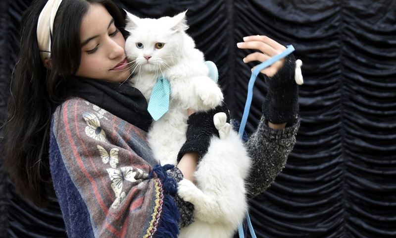 A woman carries her cat during a pet show in Peshawar, Pakistan, on Dec. 7, 2021.(Photo: Xinhua)