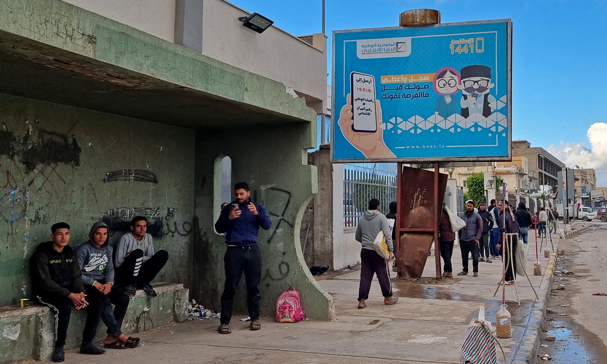 Workers walk by an electoral billboard reading in Arabic 