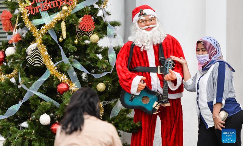 People take pictures with a Santa Claus statue and a Christmas tree at the Fatahilah Museum in Jakarta, Indonesia, Dec. 20, 2021.(Photo: Xinhua)