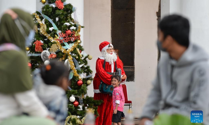 A child has fun in front of a Santa Claus statue at the Fatahilah Museum in Jakarta, Indonesia, Dec. 20, 2021.(Photo: Xinhua)