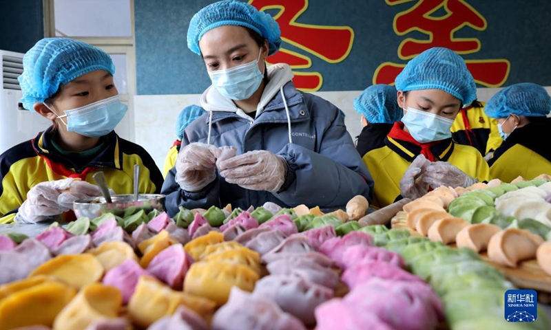 Children learn to make dumplings from their teacher in celebration of the Winter Solstice or Dongzhi in their school in Zaozhuang, east China's Shandong Province, Dec. 20, 2021. Winter Solstice, the shortest day of the year, falls on Dec. 21 this year. In Chinese culture, it marks the beginning of deep winter. It is also a time for family gatherings.(Photo: Xinhua)