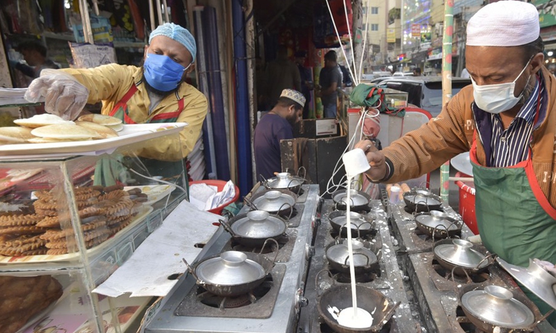 A vendor makes winter cakes known as Pitha at a roadside stall in Dhaka, Bangladesh, Dec. 20, 2021.(Photo: Xinhua)