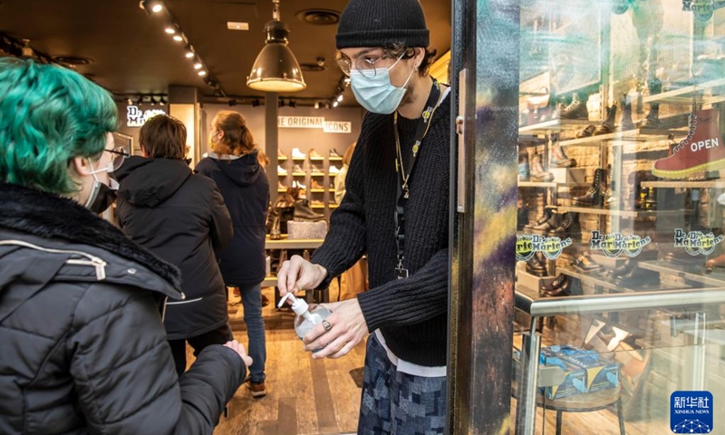 A staff member gives sanitizing gel to a customer at a store in Lille, northern France, Dec. 22, 2021. (Photo: Xinhua)