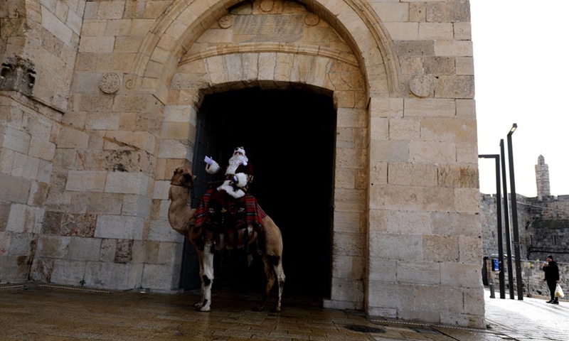 A man dressed as Santa Claus gestures as he rides a camel in Jerusalem's Old City on Dec. 23, 2021.(Photo: Xinhua)