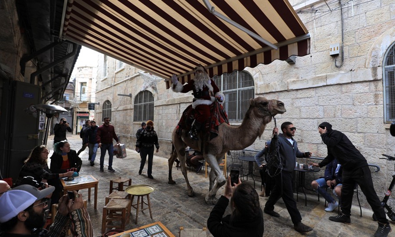 A man dressed as Santa Claus gestures as he rides a camel in Jerusalem's Old City on Dec. 23, 2021.(Photo: Xinhua)