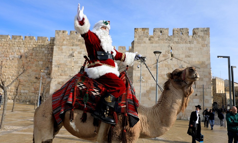 A man dressed as Santa Claus gestures as he rides a camel in Jerusalem's Old City on Dec. 23, 2021.(Photo: Xinhua)