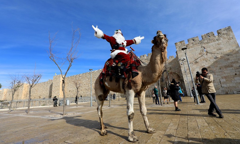 A man dressed as Santa Claus gestures as he rides a camel in Jerusalem's Old City on Dec. 23, 2021.(Photo: Xinhua)