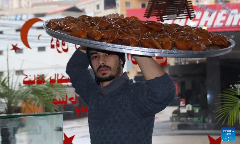 A worker carries sweets to be arranged in a sweets shop in the city of Nabatiyeh, southern Lebanon, on Dec. 22, 2021. Sweets shops see increase in prices this year in light of the deteriorating economic situation in Lebanon.(Photo: Xinhua)