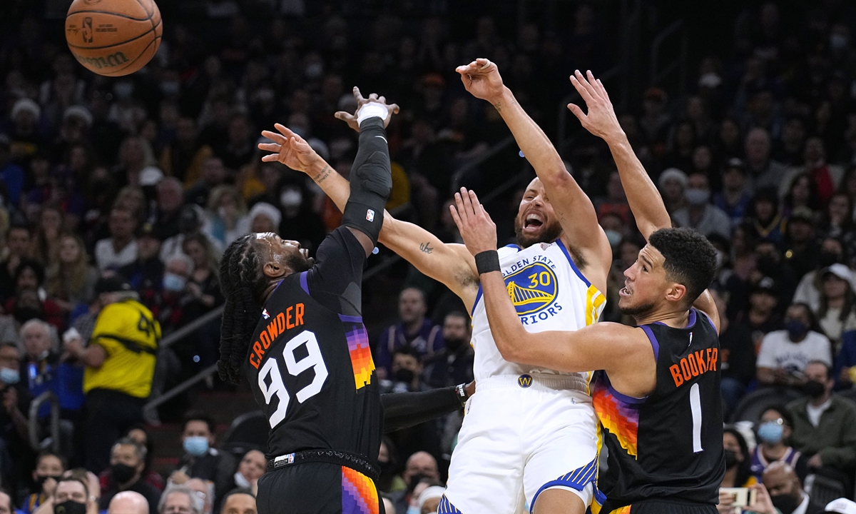 Golden State Warriors guard Stephen Curry (center) passes the ball away from Phoenix Suns forward Jae Crowder (left) and guard Devin Booker on December 25, 2021, in Phoenix, Arizona. Photo: VCG