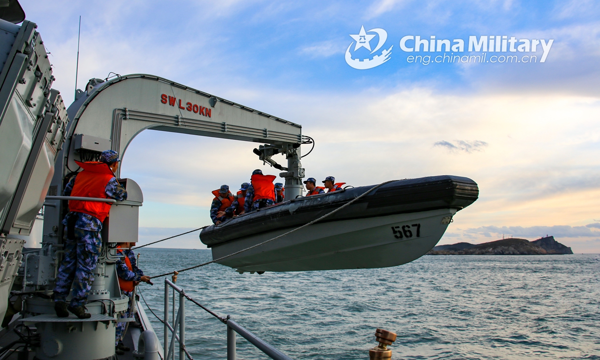 Sailors aboard a naval vessel lower a rigid-hull inflatable boat (RHIB) with a crane in preparation for a visit, board, search and seizure (VBSS) mission during a maritime training exercise in early December, 2021. (eng.chinamil.com.cn/Photo by Liu Min)