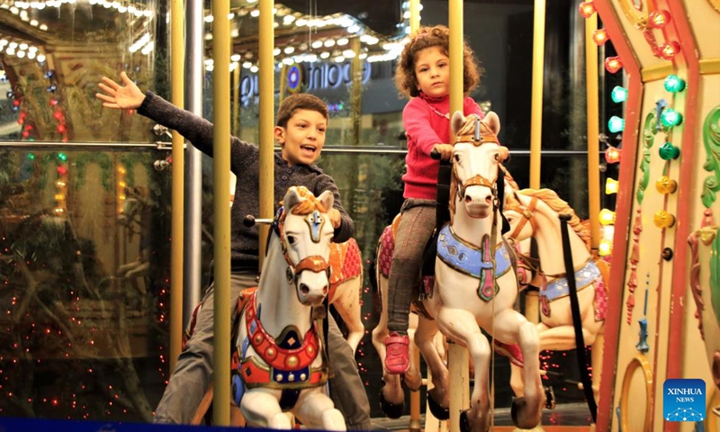 Children ride a merry-go-round in a shopping mall on the outskirts of Beirut, Lebanon, Dec. 30, 2021.Photo:Xinhua