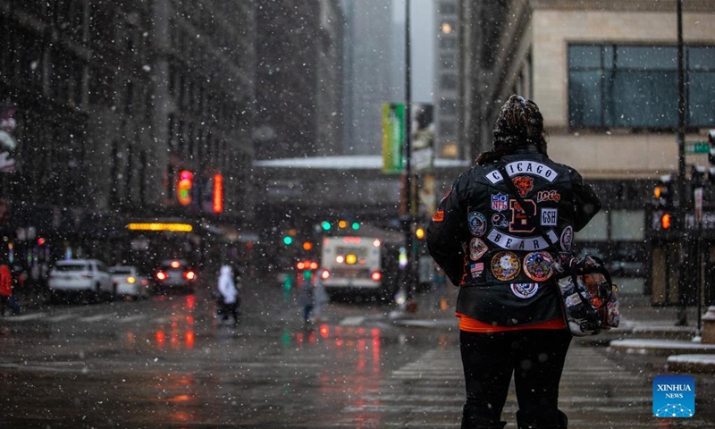 A woman waits to cross Michigan Ave in downtown Chicago, the United States, Jan. 1, 2022. A winter storm hit Chicago on Saturday, with snow accumulation expected to reach 10 to 18 centimeters. (Photo by Vincent D. Johnson/Xinhua)