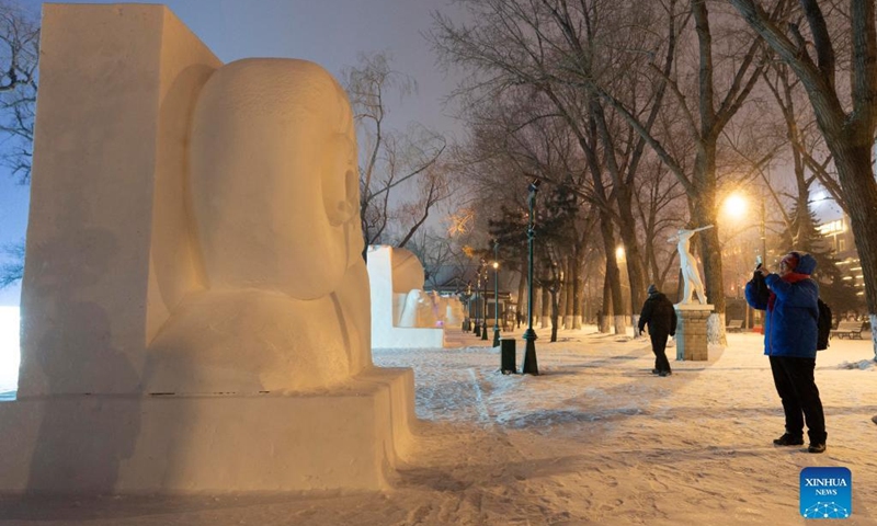 People look at a snow sculpture at a park in Harbin, northeast China's Heilongjiang Province, Jan. 1, 2022. (Xinhua/Xie Jianfei)