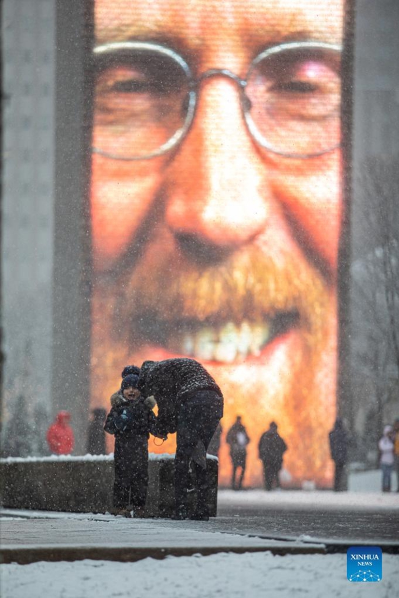 People are seen in front of the Crown Fountain in downtown Chicago, the United States, on Jan. 1, 2022. A winter storm hit Chicago on Saturday, with snow accumulation expected to reach 10 to 18 centimeters. (Photo by Vincent D. Johnson/Xinhua)