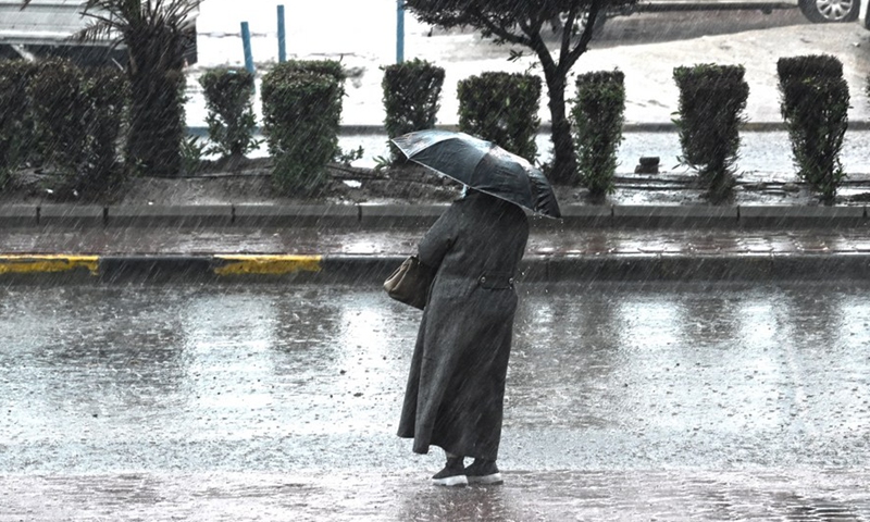 A woman walks in heavy rain on a street in Farwaniya Governorate, Kuwait, Jan. 2, 2022.Photo:Xinhua