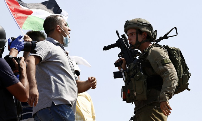 A Palestinian protester confronts an Israeli soldier during clashes following a protest against the expansion of Jewish settlements and the normalization agreements of Israel with the United Arab Emirates and Bahrain, in the West Bank village of Asira al-Qibliya near Nablus on Sept. 18, 2020.(Photo: Xinhua)