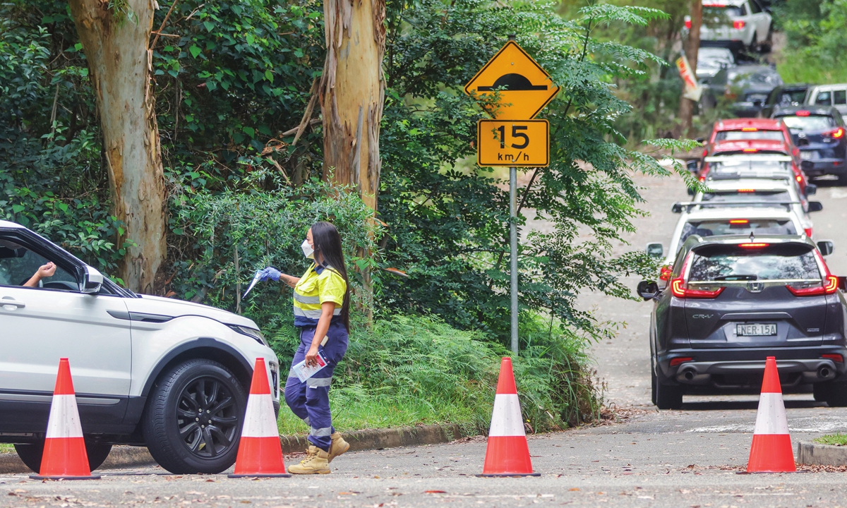 A worker hands out forms to drivers at the Warringah Aquatic Center Histopath Pathology COVID-19 Drive-through testing clinic on January 10, 2022, in Sydney, New South Wales, Australia. NSW has recorded 18 deaths from COVID-19 within one day. Photo: VCG
