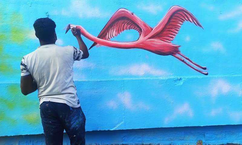 An artist gives a final touch to his flamingo artwork on the wall in Mumbai, India, Jan. 10, 2022.(Photo: Xinhua)