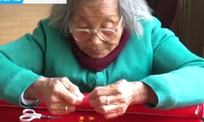 The 92-year-old woman is embroidering a marriage certificate for her granddaughter. Screeenshot from The Paper.