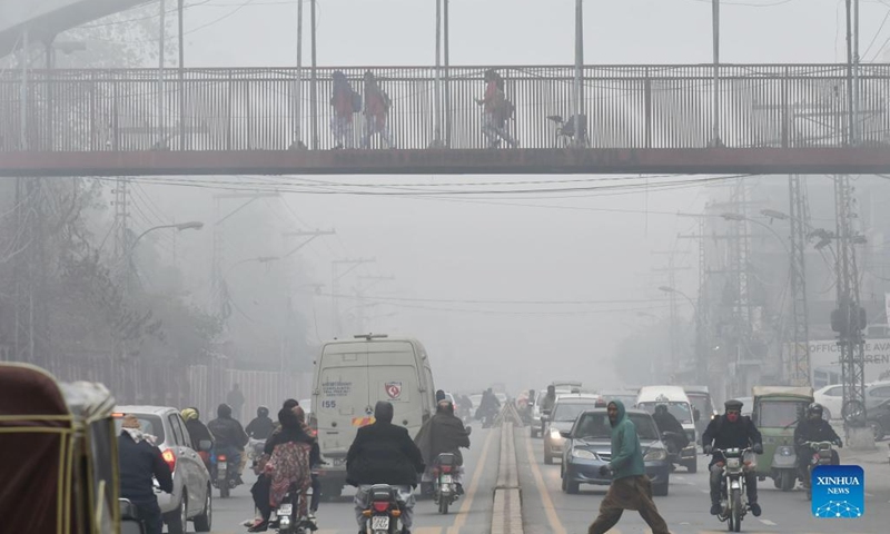 People and vehicles are seen on a road in dense fog in Lahore, Pakistan, on Jan. 13, 2022.(Photo: Xinhua)