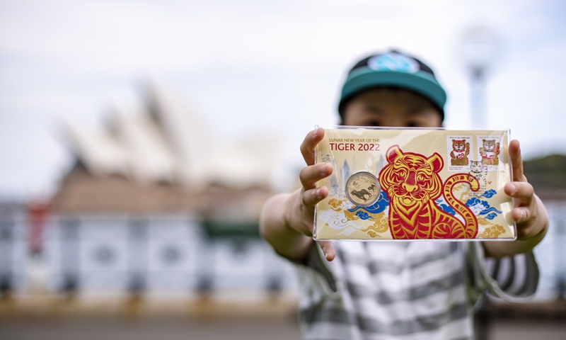 A boy shows his coin and stamps for the Year of Tiger near Sydney Opera House in Sydney, Australia, on Jan. 14, 2022.(Photo: Xinhua)