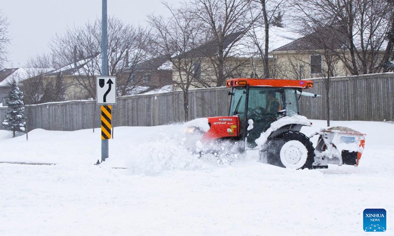 A snow plow clears snow on the sidewalk of a street during a snowy day in Mississauga, the Greater Toronto Area, Canada, on Jan. 17, 2022. Environment Canada issued a winter storm warning calling for up to 60 cm of snow in some parts of the Greater Toronto Area by Monday night.(Photo: Xinhua)