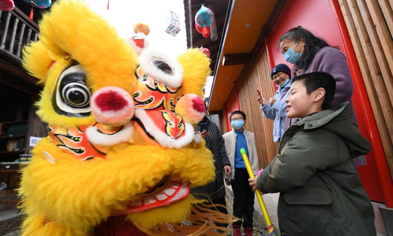 A member of a lion dance team interacts with a boy at Qiantong ancient town in Ninghai County, east China's Zhejiang Province, Jan. 20, 2022.Photo:Xinhua