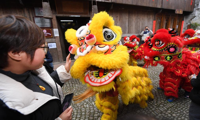 Members of a lion dance team interact with tourists at Qiantong ancient town in Ninghai County, east China's Zhejiang Province, Jan. 20, 2022.Photo:Xinhua