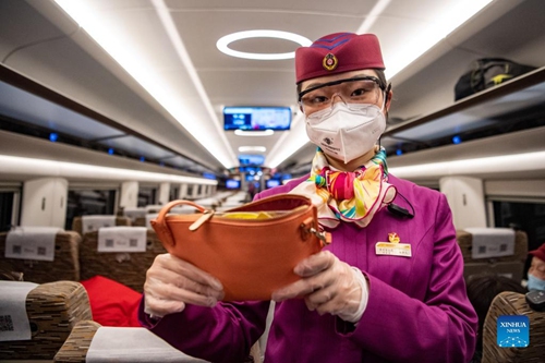 Lin Mengfan displays her pouch aboard a Fuxing bullet train travelling on the Chendu-Chongqing Railway in southwest China, Jan. 27, 2022. (Xinhua/Tang Yi)


