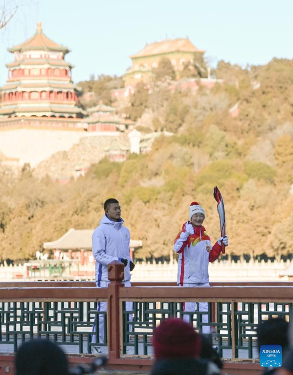 Torch bearer Ding Ning (R) runs with the torch during the Beijing 2022 Olympic Torch Relay at the Summer Palace in Beijing, capital of China, Feb. 4, 2022. (Xinhua/Chen Yehua)