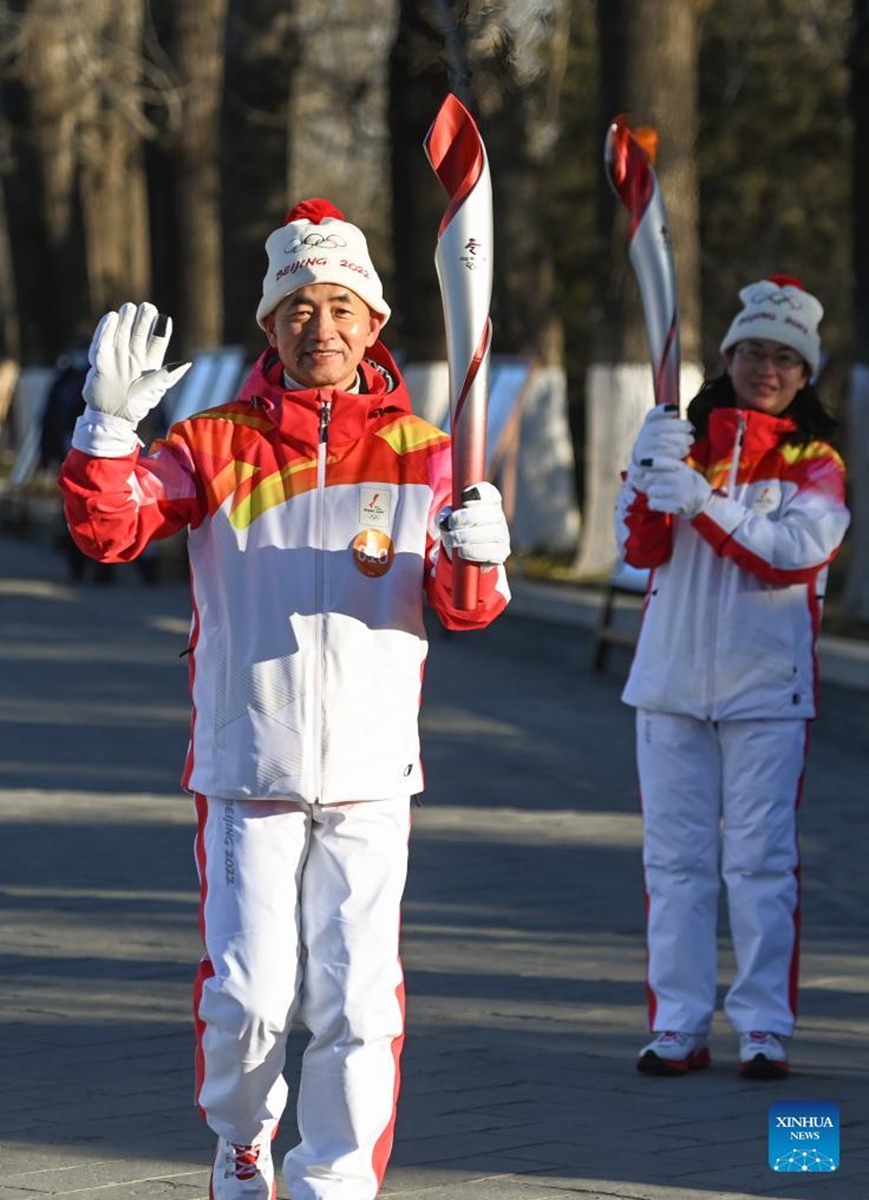 Torch bearer Su Weiqing (L) runs with the torch during the Beijing 2022 Olympic Torch Relay at the Summer Palace in Beijing, capital of China, Feb. 4, 2022. (Xinhua/Chen Yehua)