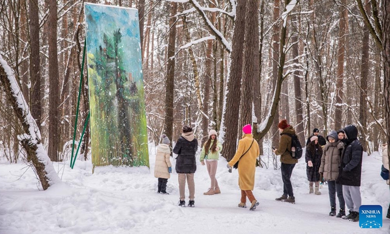 People view a painting at an open-air art exhibition titled White Forest in Malevich Park outside Moscow, Russia, on Feb. 6, 2022.Photo;Xinhua