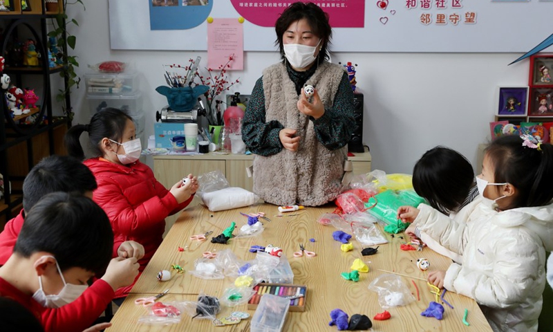 Shang Yue'e, a community volunteer, teaches children to make Bing Dwen Dwen, the mascot for the Beijing 2022 Olympic Winter Games, with colored clay at Xidu sub-district of Fengxian District in east China's Shanghai, Feb. 10, 2022.(Photo: Xinhua)