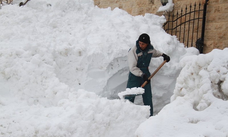 A young man shovels heavy snow in front of his shop in the town of Bcharre, northern Lebanon, on Jan. 28, 2022.Photo:Xinhua