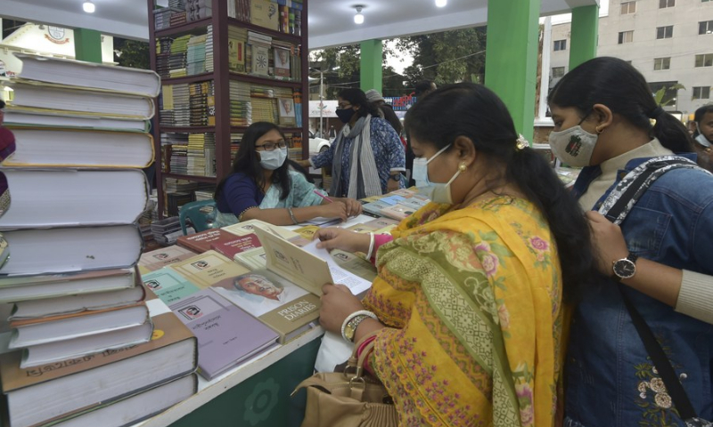 People read books at a stall during a book fair in Dhaka, capital of Bangladesh, on Feb. 15, 2022. (Photo: Xinhua)