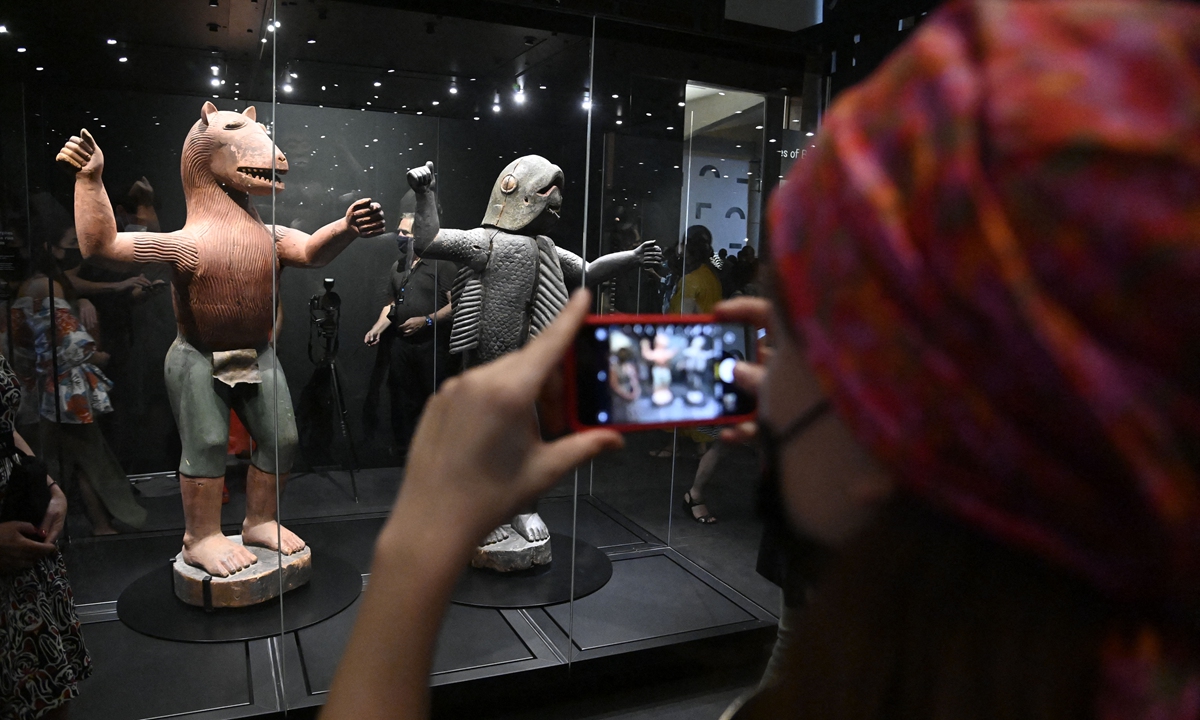 A visitor takes a photo of anthropo-zoomorphic statues during the exhibition of returned seized Benin artifacts and exhibition of contemporary artworks at the presidency in Benin's capital Cotonou, on February 18, 2022. Photo: AFP