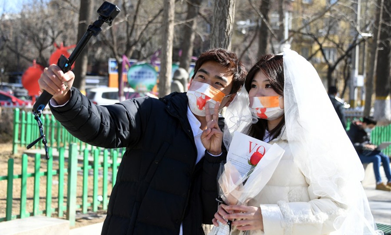 A couple poses for a photo outside a marriage registry of Haidian District in Beijing, capital of China, Feb. 22, 2022.(Photo: Xinhua)