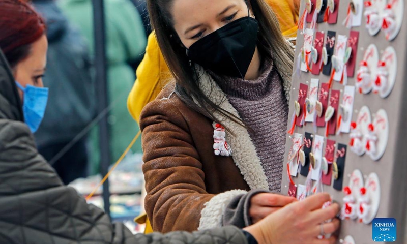 People look at small handmade figurines called Martisor during the Martisor Fair in Bucharest, capital of Romania, Feb. 26, 2022. Martisor is a small decoration tied with a red-and-white twisted string, given to women on the 1st of March as a token of appreciation, love or friendship and as a wish of health, being at the same time a symbol of the coming spring. (Photo by Cristian Cristel/Xinhua)