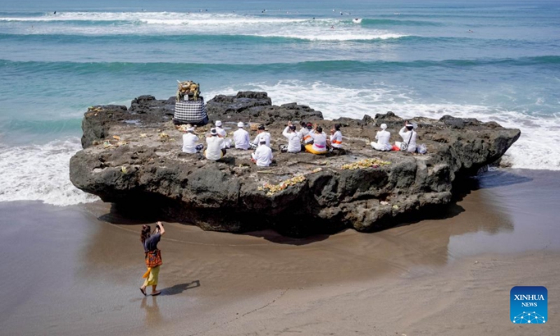 A woman takes pictures of Indonesian Hindu devotees who are participating in a Melasti ceremony at Cangu Beach in Bali, Indonesia, Feb. 28, 2022. Indonesian Hindus hold the Melasti ceremony before celebrating the Nyepi Day, the Balinese Day of Silence.(Photo: Xinhua)
