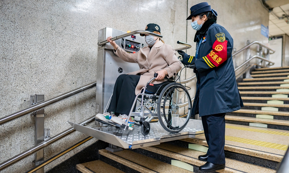 An employee at a subway station in Beijing helps a passenger with physical disablity use the accessibility facility on March 1, 2022 as the capital city enhances accessibility facilities and services ahead the Beijing 2022 Paralympic Winter Games, which will kick off on March 4. Photo: VCG