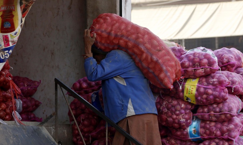 A worker carries a sack of onion at a vegetable market in Islamabad, capital of Pakistan, on Feb. 28, 2022.(Photo: Xinhua)