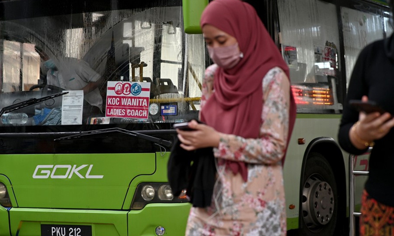 A woman wearing face mask walks in front of a ladies coach at a bus station in Kuala Lumpur, Malaysia, March 7, 2022.(Photo: Xinhua)