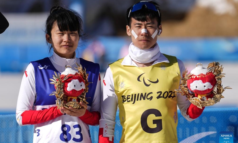 Bronze medalist Wang Yue (left) of China, together with her guide Li Yalin, poses on the podium after the Para Biathlon Women's Middle Distance Vision Impaired event of the Beijing 2022 Winter Paralympic Games in National Biathlon Center in Zhangjiakou, North China's Hebei Province, March 8, 2022. Photo: Xinhua/Peng Ziyang