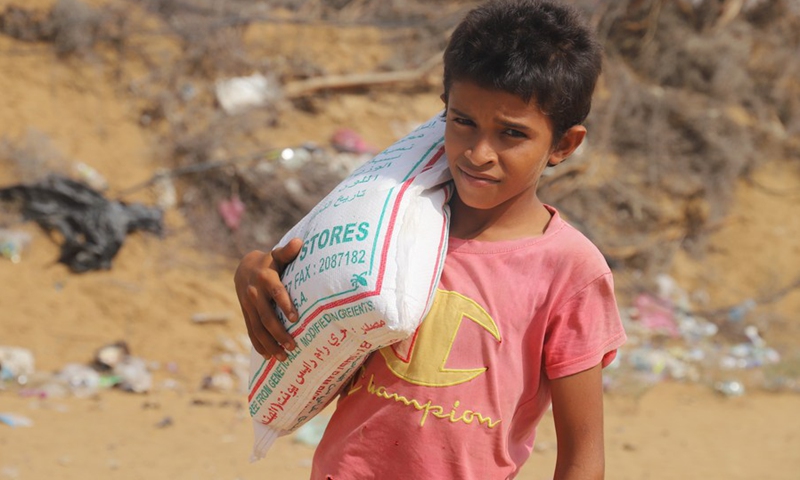 A Yemeni boy carries a bag of wheat that he received from a charity group, in Midi District, Hajjah province, northern Yemen on March 7. 2022.(Photo: Xinhua)