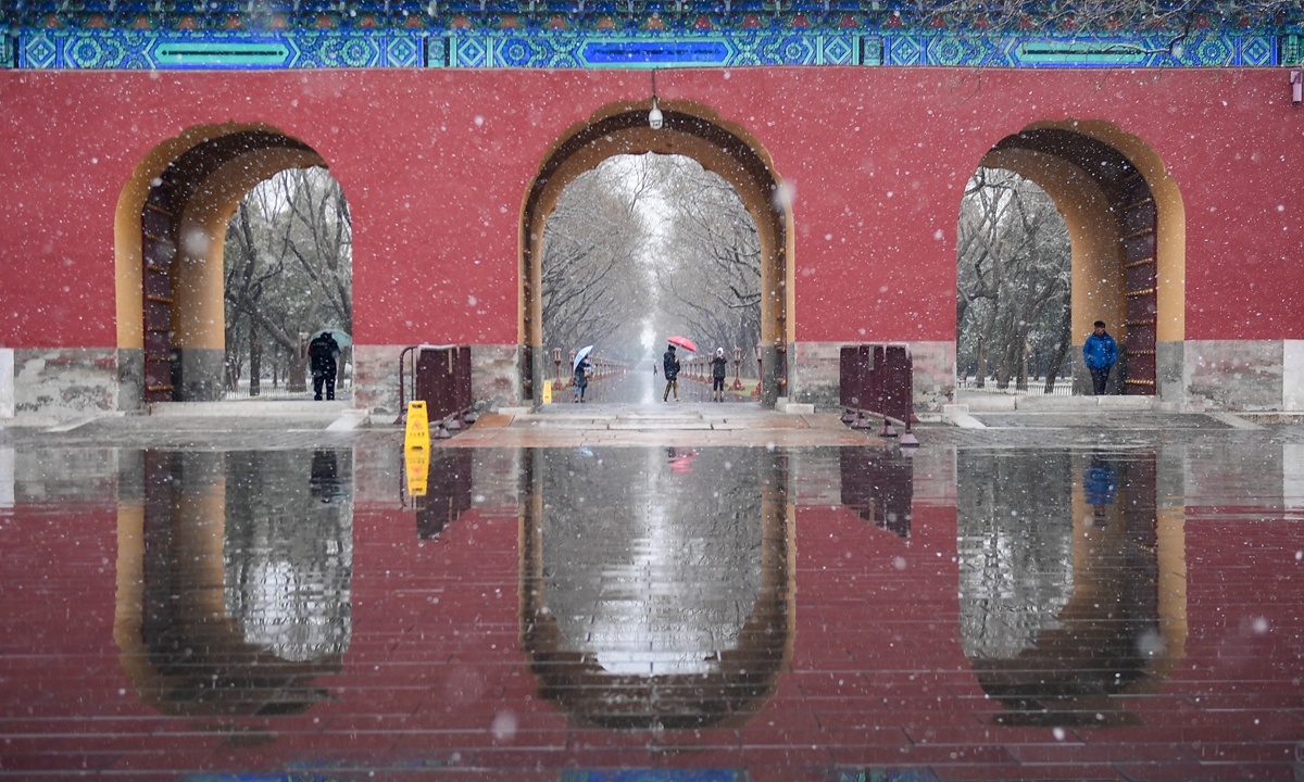 Tourists visit the Temple of Heaven Park in Beijing when a rare spring snow falls on March 17, 2022. The temperature dropped to -2 C during the day and the snowy weather caused much inconvenience to commuters. Many places in northern China saw a cold wave and snowfall, even heavy snow, the same day. Photo: cnsphoto 