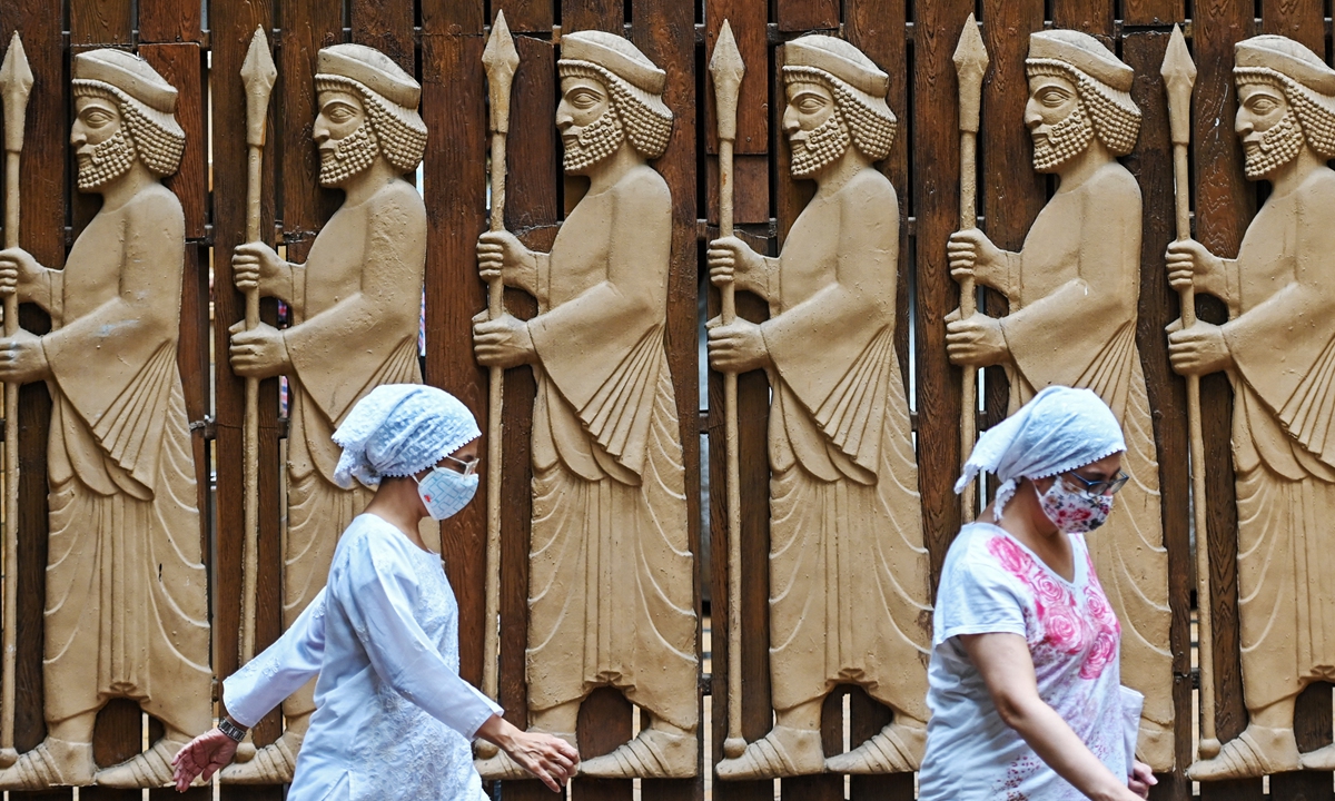 Parsi women walk past relief figures of knights on the Parsi New Year 