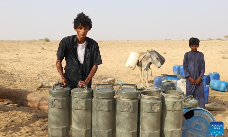 People stand by water tanks at a charitable water station in Abs District, Hajjah province, Yemen, on March 21, 2022.(Photo: Xinhua)