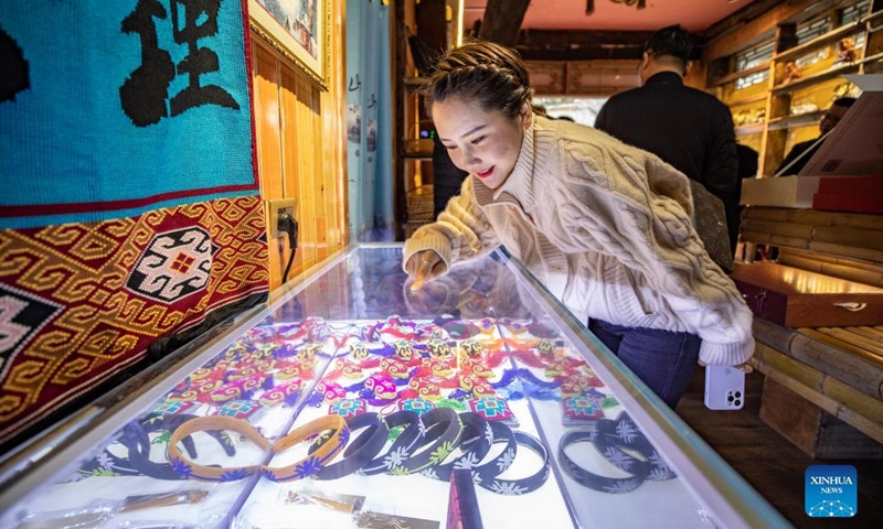 A visitor selects products of Xilankapu, which is a kind of Tujia brocade, displayed at Xiaonanhai Town of Qianjiang District in southwest China's Chongqing, March 22, 2022. Xilankapu, also known as knitting Floral Bedclothes, was listed as national intangible cultural heritage in 2006.(Photo: Xinhua)